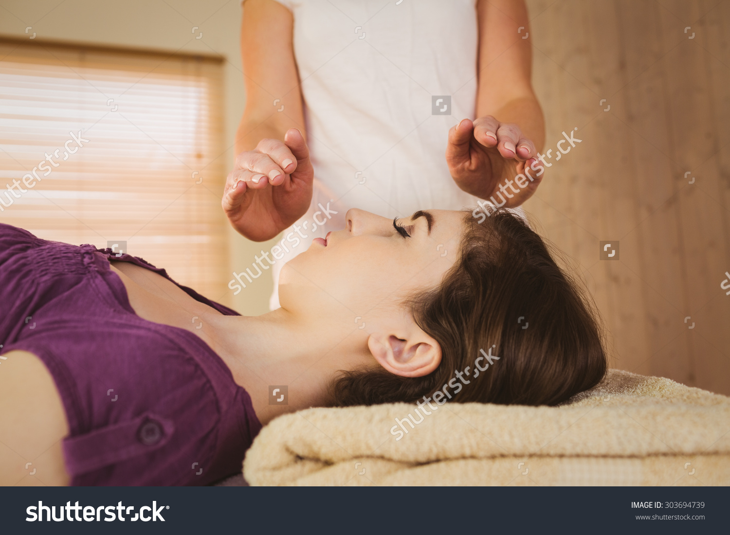 stock-photo-young-woman-having-a-reiki-treatment-in-therapy-room-303694739